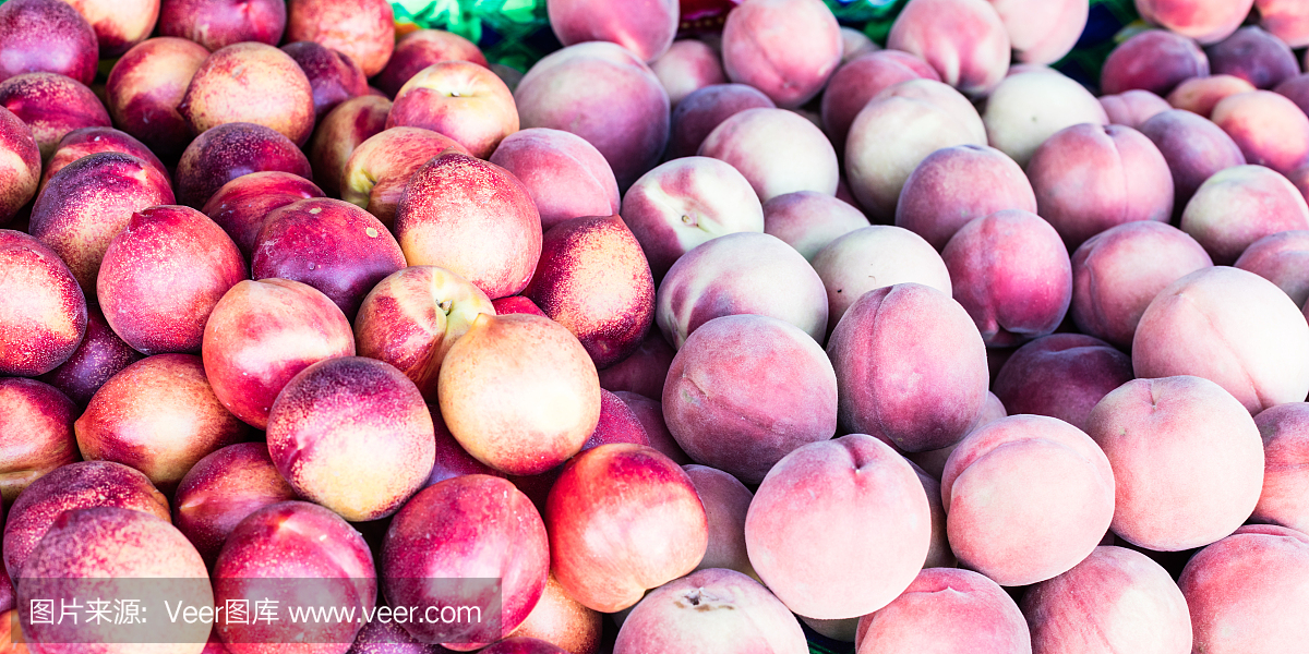 在农贸市场日,水果摊上摆满了油桃和桃子。